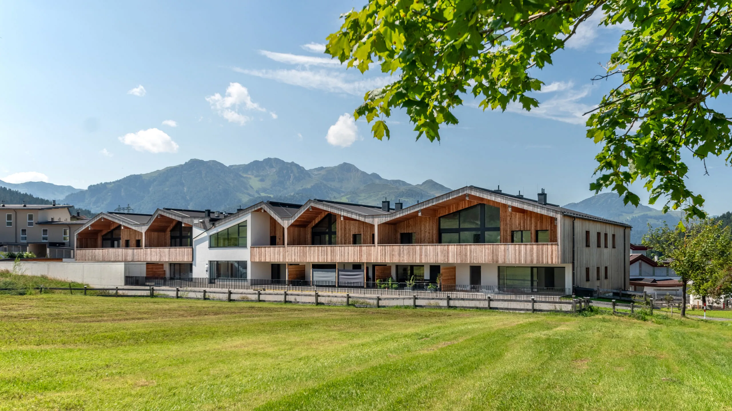 Wohnprojekt von Pletzer Immobilien im alpinen Stil mit Holzfassade und Bergkulisse.